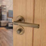 This is an image showing Alexander & Wilks - Spitfire Hex Lever on Round Rose - Italian Brass aw224ib available to order from Trade Door Handles in Kendal, quick delivery and discounted prices.