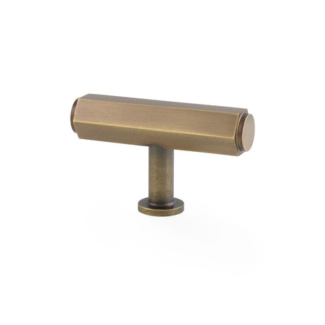 This is an image showing Alexander & Wilks - Vesper Hex T - Bar Cabinet Knob - Antique Brass aw829-55-ab available to order from Trade Door Handles in Kendal, quick delivery and discounted prices.