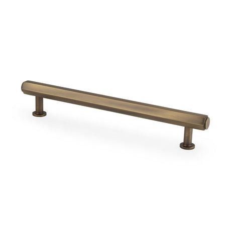 This is an image showing Alexander & Wilks - Vesper Hex T - Bar Cabinet Pull - Antique Brass - 160mm C/C aw830-160-ab available to order from Trade Door Handles in Kendal, quick delivery and discounted prices.