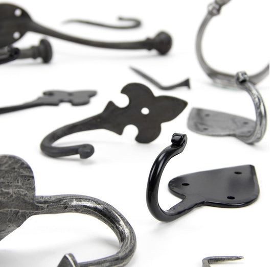 Image showing a range of traditional coat hooks by From The Anvil in Pewter, Black and Beeswax. Available to order from Trade Door Handles in Kendal