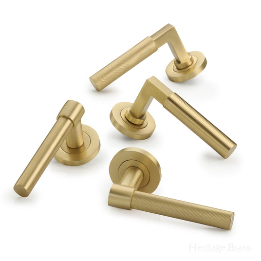 This image shows a range of Heritage Brass Signac Door levers on a round rose in Satin Brass.  Available to order from Trade Door Handles in Kendal