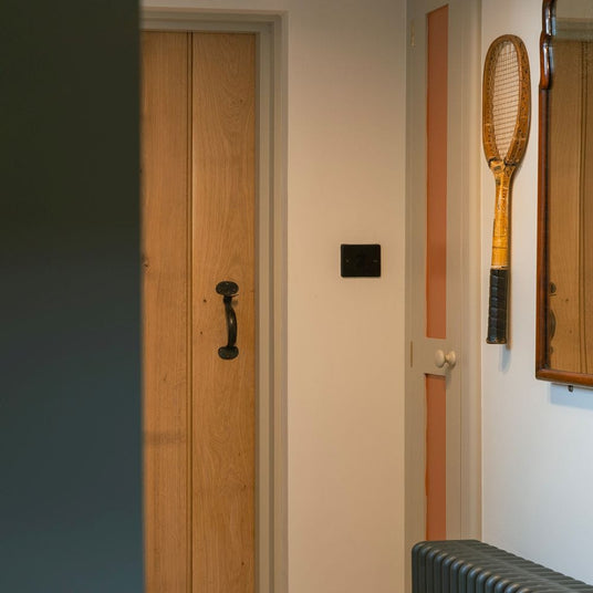 This is an image showing The Anvil Beeswax Medium Bean Thumblatch on a button bead oak door