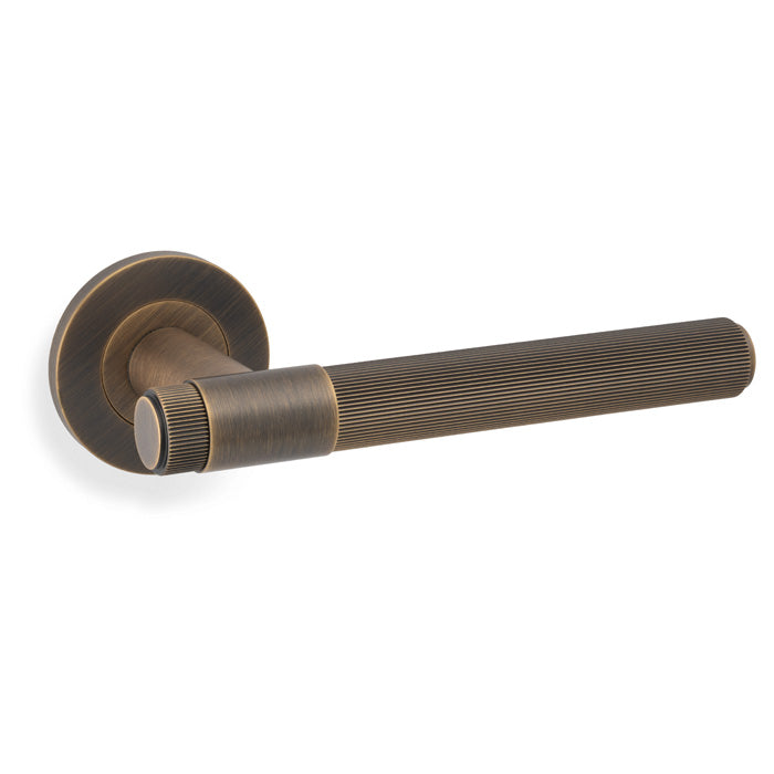 High quality image of Alexander & Wilks - Kingston Reeded lever on Round Rose-Antique Brass | Sku.AW242AB | Trade Door Handles.