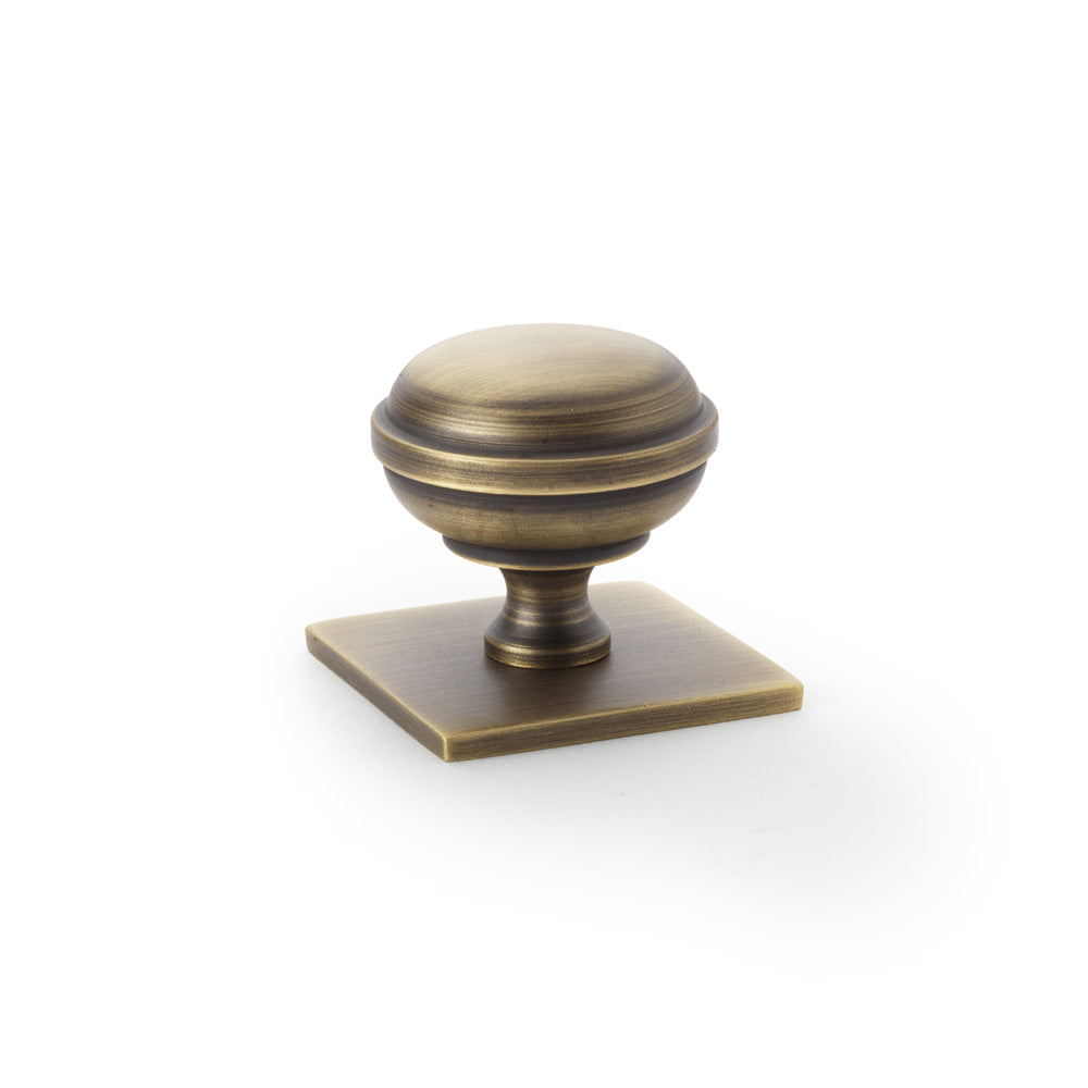 High quality image of Alexander & Wilks Quantock Cupboard Knob on Square Backplate - Antique Brass - 34mm | Sku. aw826-34-ab | Trade Door Handles.