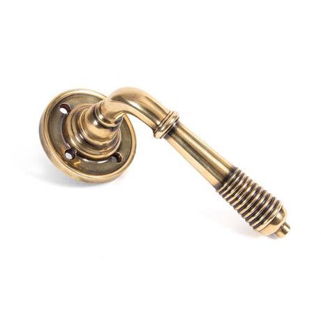 This is an image showing From The Anvil - Aged Brass Reeded Lever on Rose Set available from trade door handles, quick delivery and discounted prices