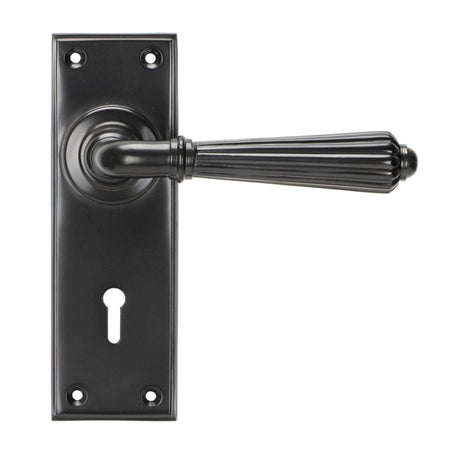 This is an image showing From The Anvil - Aged Bronze Hinton Lever Lock Set available from trade door handles, quick delivery and discounted prices