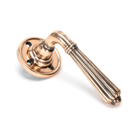 This is an image showing From The Anvil - Polished Bronze Hinton Lever on Rose Set available from trade door handles, quick delivery and discounted prices