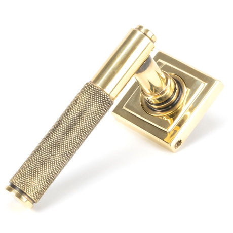 This is an image showing From The Anvil - Aged Brass Brompton Lever on Rose Set (Square) available from trade door handles, quick delivery and discounted prices