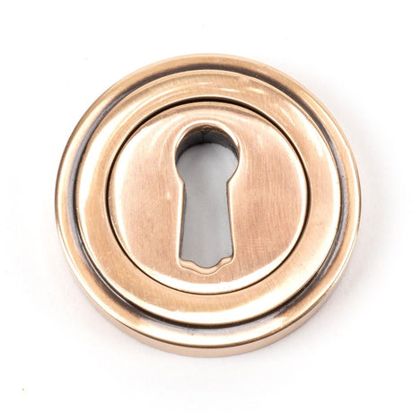 This is an image showing From The Anvil - Polished Bronze Round Escutcheon (Art Deco) available from trade door handles, quick delivery and discounted prices