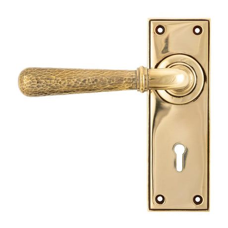 This is an image showing From The Anvil - Aged Brass Hammered Newbury Lever Lock Set available from trade door handles, quick delivery and discounted prices