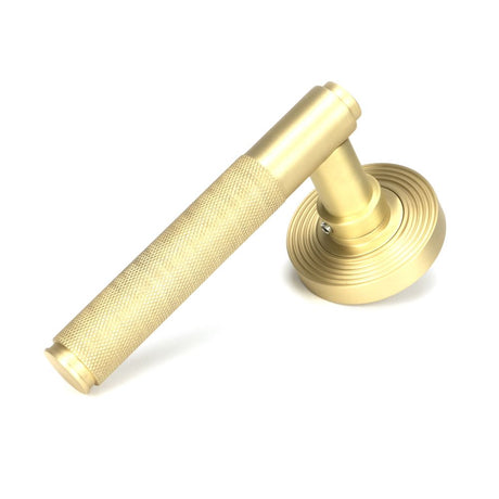 This is an image showing From The Anvil - Satin Brass Brompton Lever on Rose Set (Beehive) available from trade door handles, quick delivery and discounted prices