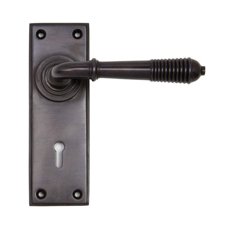 This is an image showing From The Anvil - Aged Bronze Reeded Lever Lock Set available from trade door handles, quick delivery and discounted prices