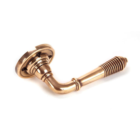 This is an image showing From The Anvil - Polished Bronze Reeded Lever on Rose Set available from trade door handles, quick delivery and discounted prices
