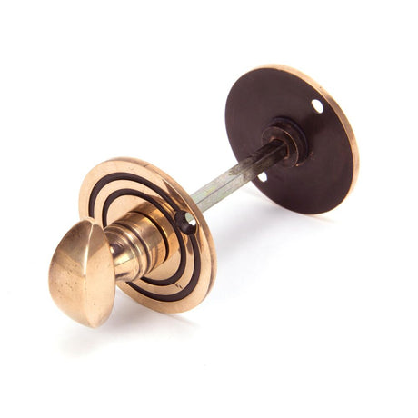This is an image showing From The Anvil - Polished Bronze Round Bathroom Thumbturn available from trade door handles, quick delivery and discounted prices