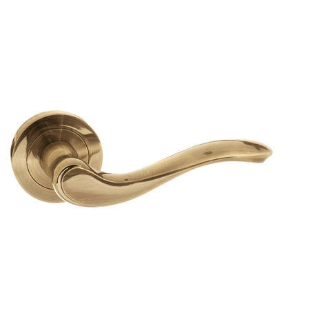 This is an image of Old English Warwick Lever on Round Rose - Antique Brass available to order from Trade Door Handles.