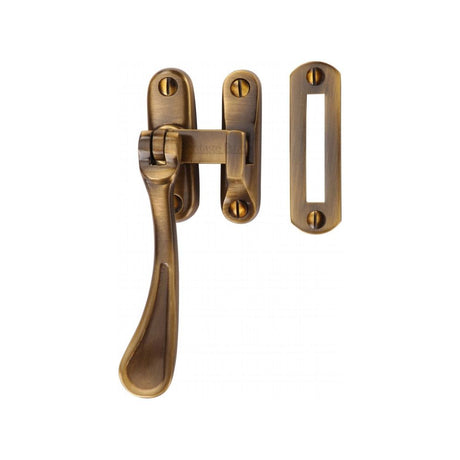 This is an image of a Heritage Brass - Casement Window Fastener Spoon Pattern Antique Brass Finish, v1003-mp-hp-at that is available to order from Trade Door Handles in Kendal.
