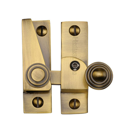 This is an image of a Heritage Brass - Sash Fastener Lockable Antique Brass Finish, v1104l-at that is available to order from Trade Door Handles in Kendal.