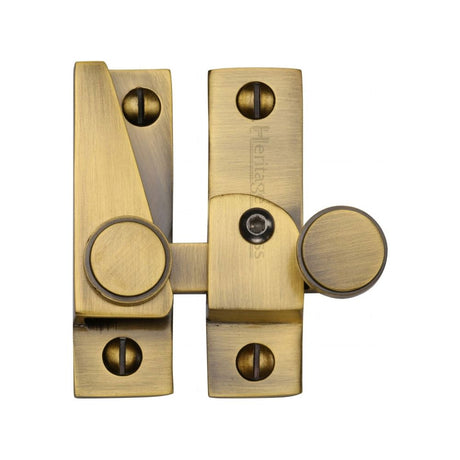 This is an image of a Heritage Brass - Sash Fastener Lockable Antique Brass Finish, v1106l-at that is available to order from Trade Door Handles in Kendal.