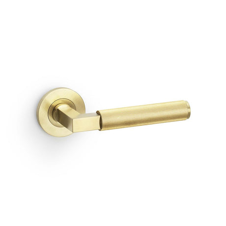 This is an image showing Alexander & Wilks Hurricane Reeded Lever on Round Rose - Satin Brass PVD aw202sbpvd available to order from Trade Door Handles in Kendal, quick delivery and discounted prices.