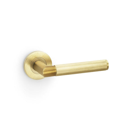 This is an image showing Alexander & Wilks Harrier Knurled Lever on Round Rose - Satin Brass PVD aw210sbpvd available to order from Trade Door Handles in Kendal, quick delivery and discounted prices.