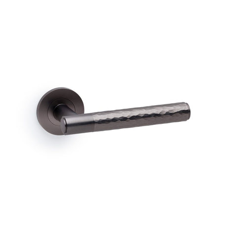 This is an image showing Alexander & Wilks Spitfire Hammered Lever on Round Rose - Dark Bronze aw223dbz available to order from Trade Door Handles in Kendal, quick delivery and discounted prices.