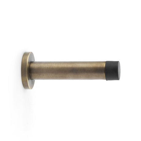 This is an image showing Alexander & Wilks Cylinder Projection Door Stop on Rose - Antique Brass aw616ab available to order from Trade Door Handles in Kendal, quick delivery and discounted prices.