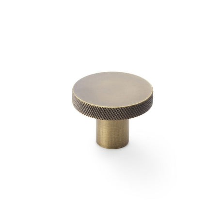 This is an image showing Alexander & Wilks Hanover Knurled Circular Cupboard Knob - Antique Brass - 38mm aw802-38-ab available to order from Trade Door Handles in Kendal, quick delivery and discounted prices.