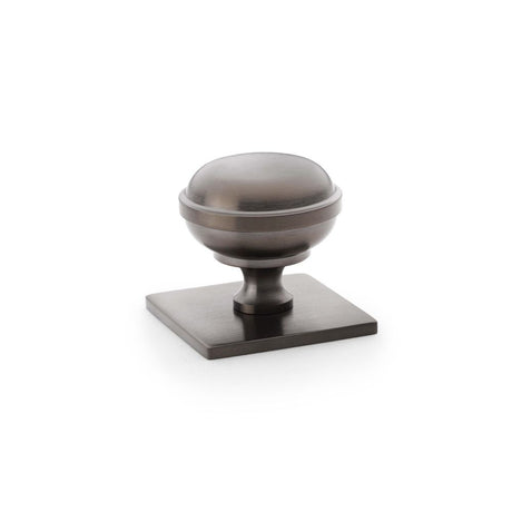 This is an image showing Alexander & Wilks Quantock Cupboard Knob on Square Backplate - Dark Bronze PVD - 34mm aw826-34-dbzpvd available to order from Trade Door Handles in Kendal, quick delivery and discounted prices.