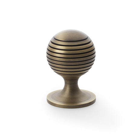 This is an image showing Alexander & Wilks Caesar Cupboard Knob on Round Rose - Antique Brass - 38mm aw832-38-ab available to order from Trade Door Handles in Kendal, quick delivery and discounted prices.