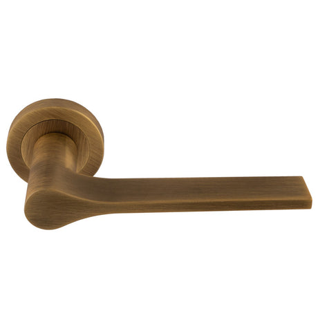 This is an image of a Manital - Vela Lever on Round Rose - Antique Brass vv5ab that is availble to order from Trade Door Handles in Kendal.