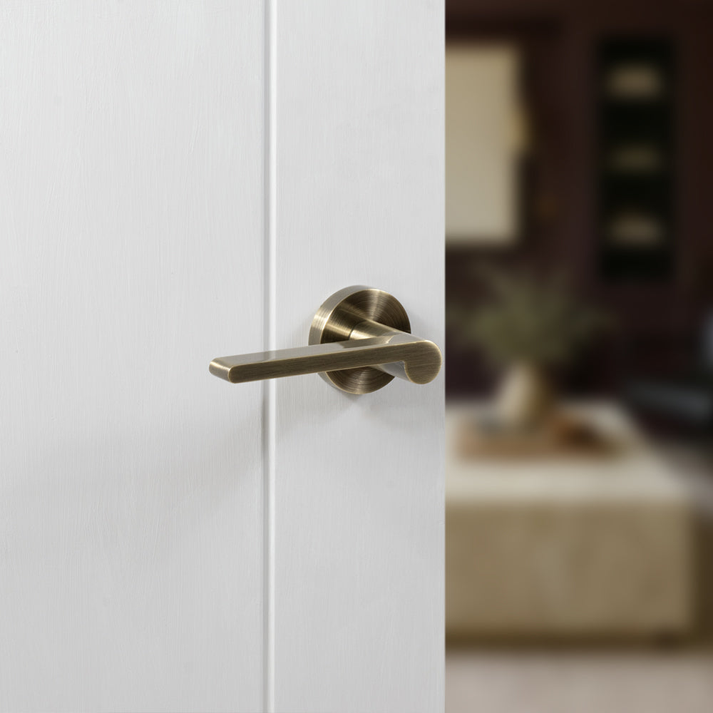 Quality image of Senza Pari Darrio Lever Door Handle on Round Rose - Antique Brass | Sku. spro218ab | available from Trade Door Handles.