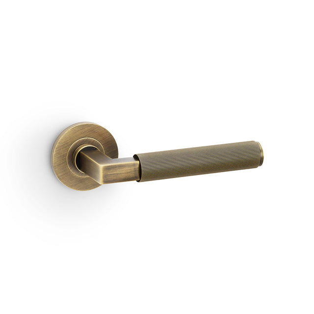 High quality image of Alexander & Wilks - Hurricane Reeded Lever on Round Rose - Antique Brass | Sku. aw202ab | Trade Door Handles.