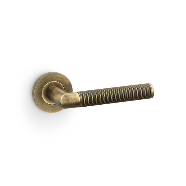High quality image of Alexander & Wilks - Harrier Knurled Lever on Round Rose - Antique Brass | Sku. aw210ab | Trade Door Handles.