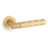 This is an image showing Alexander & Wilks Spitfire Diamond Cut Lever on Round Rose - Satin Brass PVD - aw226-SBPVD available to order from Trade Door Handles in Kendal, quick delivery and discounted prices.