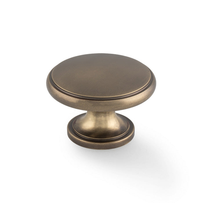 This is an image of Alexander & Wilks - Cambridge Round Cupboard Knob - Antique Brass available to order from Trade Door Handles in Kendal, quick delivery and discounted prices.