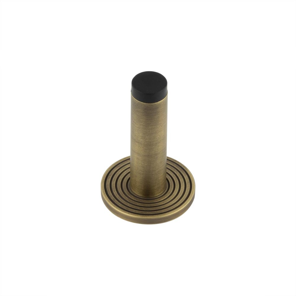 This is an image showing the Frelan - Burlington Plain Wall Mounted Door Stops Reeded Rose Antique Brass available to order from Trade Door Handles in Kendal