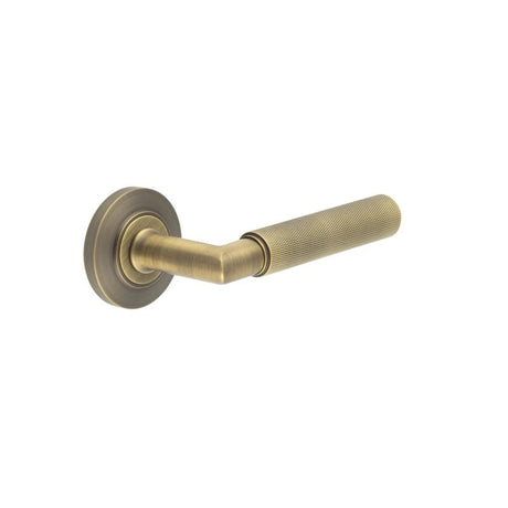 This is an image showing the Frelan - Piccadilly Door Handle on Chamfered Rose Antique Brass available to order from Trade Door Handles in Kendal