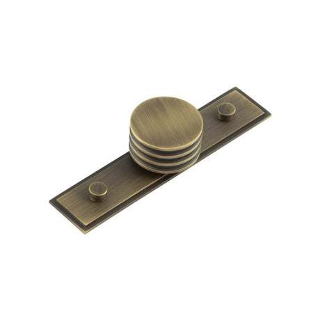 This is an image showing the Frelan - Sturt Cupboard Knobs 40mm Stepped Antique Brass available to order from Trade Door Handles in Kendal