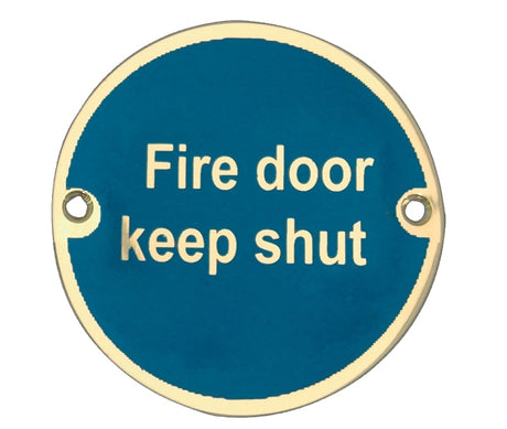 This is an image showing the Frelan - Fire Door Keep Shut' - Signage 75mm Dia. - Polished Brass available to order from Trade Door Handles in Kendal