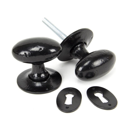 This is an image showing From The Anvil - Black Oval Mortice/Rim Knob Set available from trade door handles, quick delivery and discounted prices