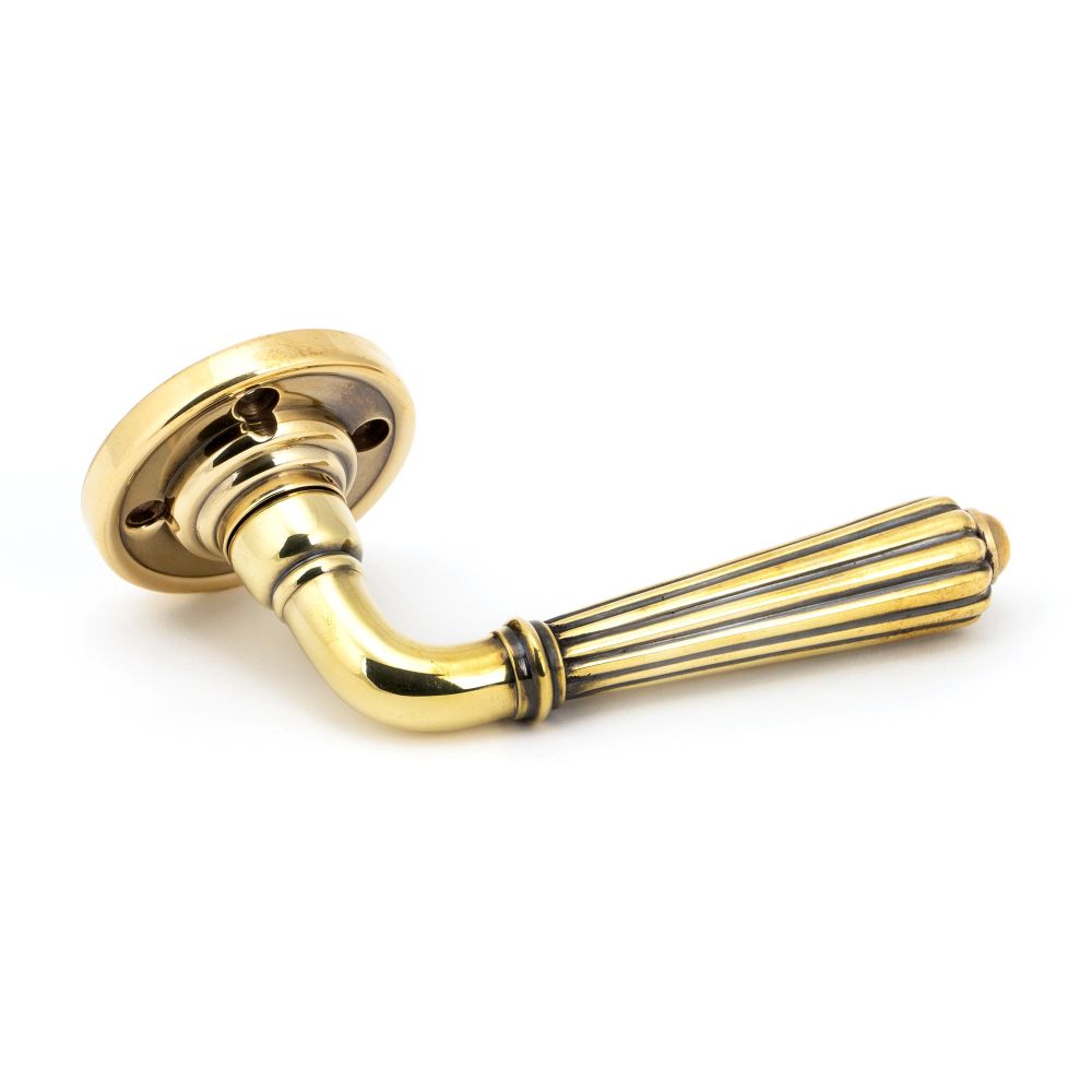 This is an image showing From The Anvil - Aged Brass Hinton Lever on Rose Set available from trade door handles, quick delivery and discounted prices