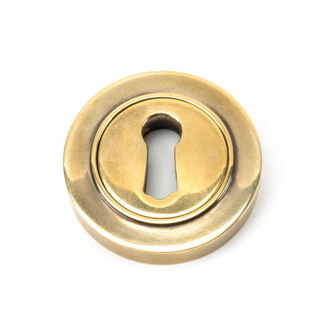 This is an image showing From The Anvil - Aged Brass Round Escutcheon (Plain) available from trade door handles, quick delivery and discounted prices