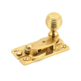 This is an image showing From The Anvil - Polished Brass Beehive Sash Hook Fastener available from trade door handles, quick delivery and discounted prices