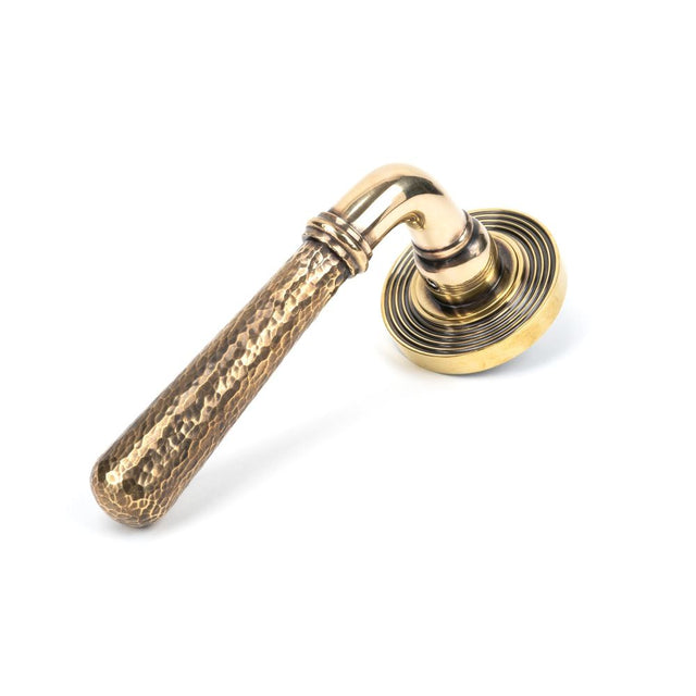 This is an image showing From The Anvil - Aged Brass Hammered Newbury Lever on Rose Set (Beehive) available from trade door handles, quick delivery and discounted prices