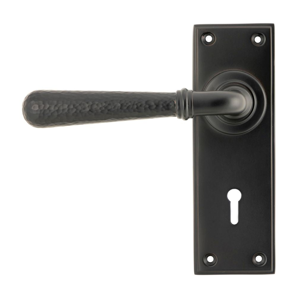 This is an image showing From The Anvil - Aged Bronze Hammered Newbury Lever Lock Set available from trade door handles, quick delivery and discounted prices