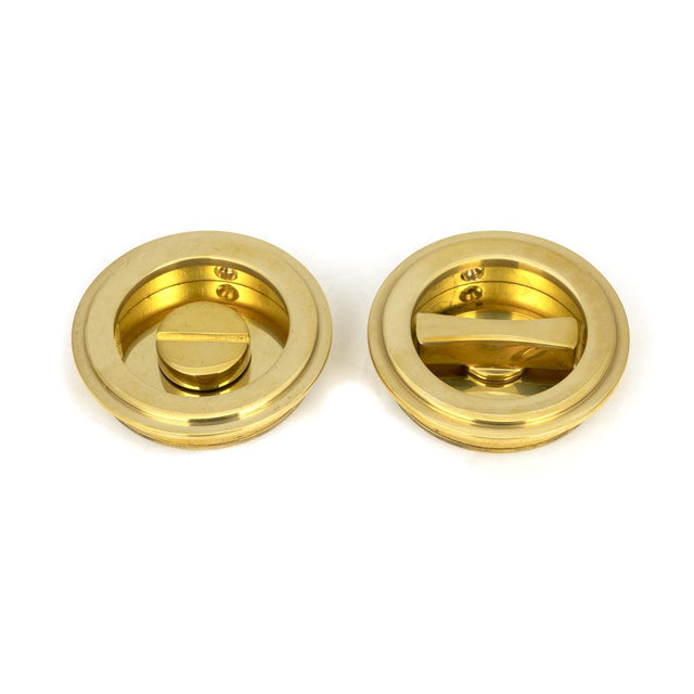 This is an image showing From The Anvil - Polished Brass 60mm Art Deco Round Pull - Privacy Set available from trade door handles, quick delivery and discounted prices