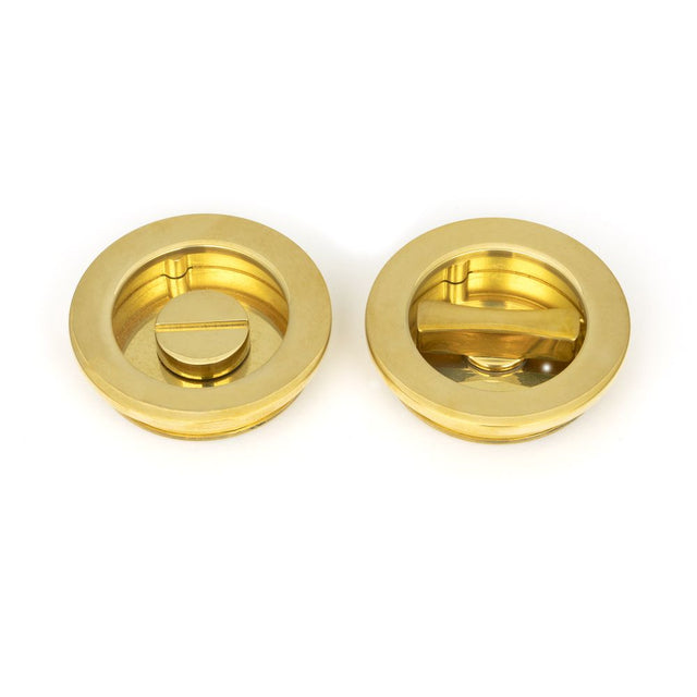 This is an image showing From The Anvil - Polished Brass 60mm Plain Round Pull - Privacy Set available from trade door handles, quick delivery and discounted prices