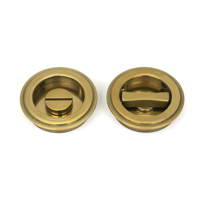 This is an image showing From The Anvil - Aged Brass 60mm Art Deco Round Pull - Privacy Set available from trade door handles, quick delivery and discounted prices