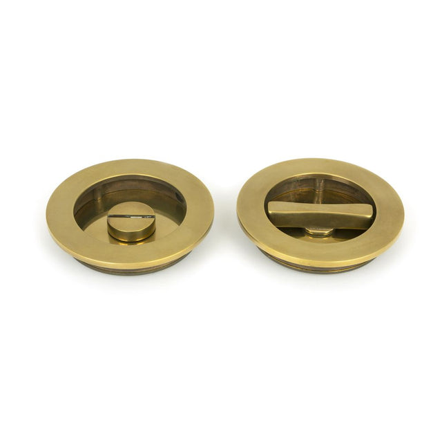 This is an image showing From The Anvil - Aged Brass 75mm Art Deco Round Pull - Privacy Set available from trade door handles, quick delivery and discounted prices