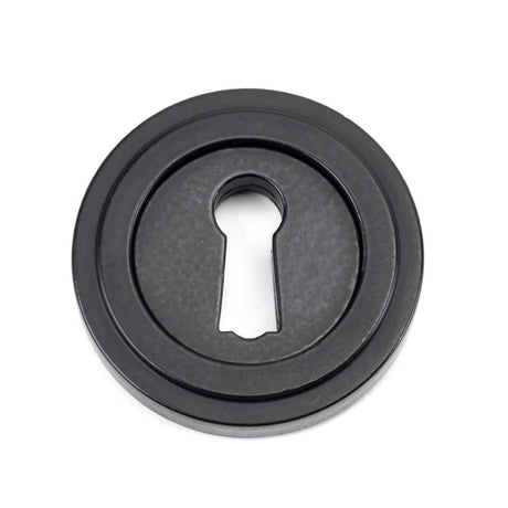 This is an image showing From The Anvil - Matt Black Round Escutcheon (Art Deco) available from trade door handles, quick delivery and discounted prices
